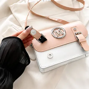Détail du petit sac carré rose avec logo M en métal argenté et fermeture magnétique chic