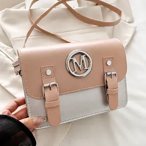 Detail of pink and silver square crossbody bag with metallic M logo and strap buckles
