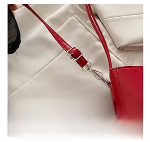 Detailed close-up of adjustable silver hardware on a glossy red baguette shoulder bag