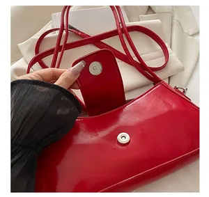 Detail of metal magnetic closure on a glossy red patent leather underarm handbag