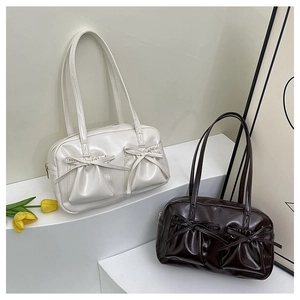 Detailansicht glänzender Schultertaschen in Creme und Dunkelbraun mit Schleifendekor