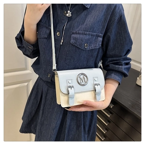 Détail du sac bandoulière bleu et beige avec boucle M en métal et sangles décoratives chic