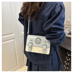 Detail of minimalist two-tone crossbody bag with silver M-buckle on vintage leather