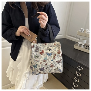 Detailed view of floral butterfly jacquard tote bag held by a model in casual setting