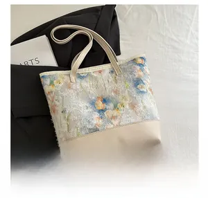 Detailed embroidery of floral patterns on a cream canvas tote bag with shoulder straps