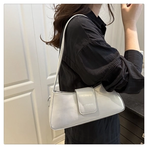 Minimalist white leather baguette bag worn as an underarm shoulder bag with logo detail