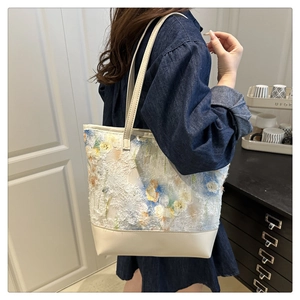 Detail of vintage floral embroidery on leather tote bag worn by a model in lifestyle setting