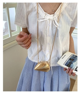 Detailed view of creative mini gold shell evening bag with wavy texture and metal chain