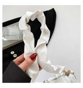 Détail de la poignée froncée blanche avec boucle dorée sur un sac à bandoulière chic