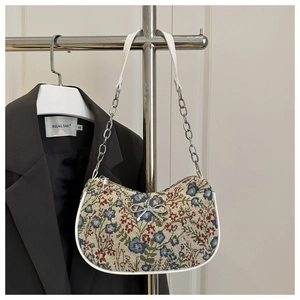 Detalle del bolso hobo de lona floral con cadena plateada y lazo metálico decorativo