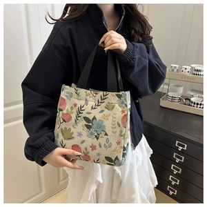 Detailed texture of floral embroidered tote bag held by model in casual lifestyle setting