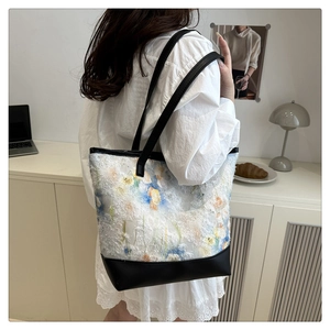 Detailed view of floral tote bag with blue and yellow patterns and black leather strap