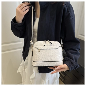 Detail of white woven texture crossbody bag with wide strap and shell shape design