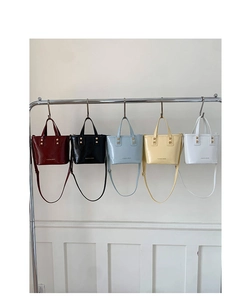 Row of colorful vegan leather mini bucket bags hanging on a rack in various vibrant colors