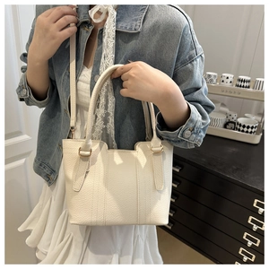 Détails du sac fourre-tout en cuir crème avec texture grainée et anneaux métalliques dorés