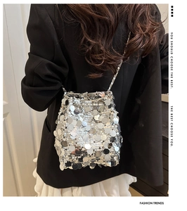 Borsa a secchiello con paillettes argento e catena in metallo su blazer nero