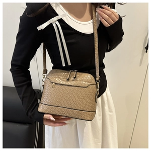 Detail of khaki faux-crocodile crossbody bag with gold zippers and adjustable strap
