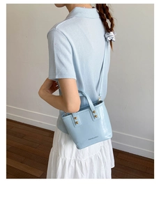 Detail of light blue leather bucket bag with gold rivets and fine shoulder strap