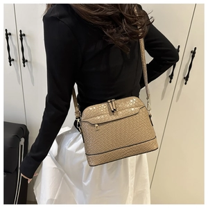 Khaki woven crossbody bag with golden hardware shown from a side view on a model