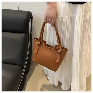 Détail du sac seau en cuir grainé marron avec coutures verticales et texture douce