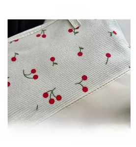 Détail du sac cabas en toile à motif cerise avec base en cuir crème et coutures