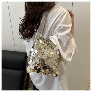 Detailed close-up of a shimmering gold sequin bucket bag with a luxury metal chain strap