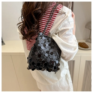 Detail of a black sequin bucket bag with silver chain strap shown in a lifestyle setting