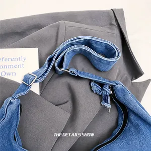 Detail of adjustable denim shoulder strap with silver metal buckle on crossbody bag