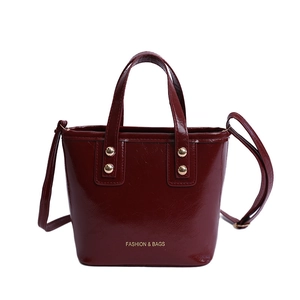 Elegant wine red bucket bag in glossy patent leather with top handles and shoulder strap