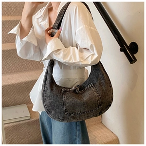 Detail of vintage denim crossbody bag featuring contrast stitching and washed black fabric