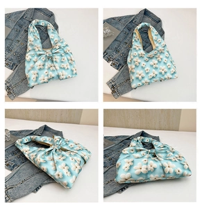 Macro detail of a light blue quilted floral tote bag with 3D flower and bow accents