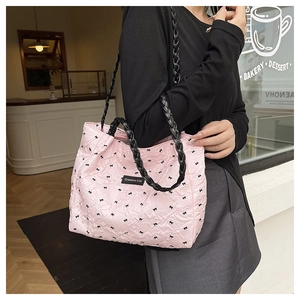 Detail of pink quilted tote bag featuring black bow patterns and woven rope handles