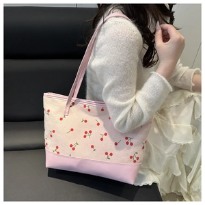 Detail of pink corduroy tote bag featuring cherry embroidery and leather strap textures
