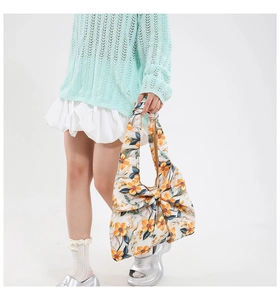 Detalle de bolso de lona floral con lazo grande y estampados de flores naranjas