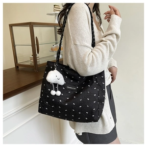 Detail of black quilted tote bag with white bow pattern and cute cloud plush charm