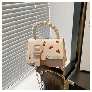 Détail de sac en cuir à imprimé cerises avec poignée en perles et chaîne dorée