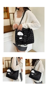 Detail of black quilted tote bag with white bow patterns and fluffy cloud charm accessory