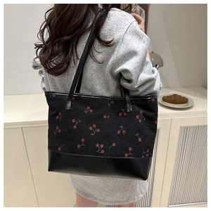 Détail d'un grand cabas en velours noir avec motifs cerises et fond en cuir