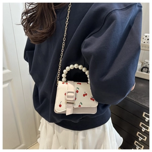 Détail du mini sac bandoulière en cuir blanc avec imprimés cerise et anse perle