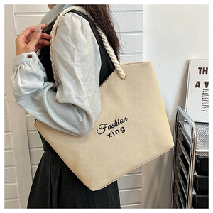 Détail du sac cabas en toile côtelée beige clair avec anses en corde blanche et logo noir
