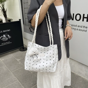 Quilted white tote bag with black bow patterns and a cloud plush charm on braided strap