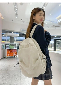 Detail view of large cream corduroy backpack featuring side black elastic drawstrings