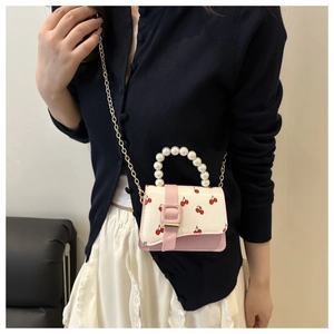 Détail du sac à main imprimé cerise avec poignée en perles et fermoir boucle rose