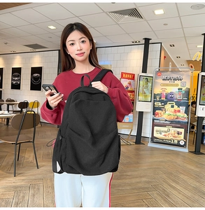 Detail of black corduroy backpack showing ribbed texture and drawstring side pocket