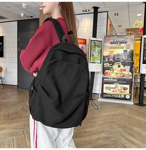 Detail view of black corduroy backpack with side drawstring pockets and adjustable straps