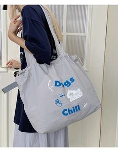 Detail of grey drawstring tote bag with cartoon dog print and wide shoulder strap