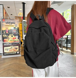 Close-up of black corduroy backpack with vertical texture and front zipper pocket
