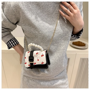 Détail du mini sac imprimé cerise avec poignée en perles et chaîne dorée