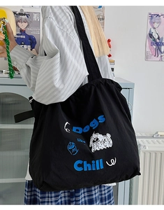 Close-up of black canvas tote bag with blue 'Dogs like Chill' text and puppy graphic