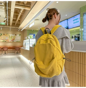 Detail of yellow corduroy backpack showing large front pocket and soft ribbed texture
